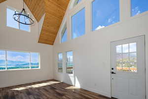 Entrance foyer featuring a mountain view, dark wood-style floors, a high wood ceiling, hanging lights, and plenty of natural light