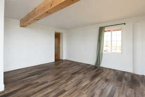 Unfurnished room with dark wood finished floors, beamed ceiling, and a textured ceiling