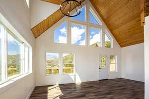 Unfurnished living room featuring dark wood-style floors, a mountain view, a high wooden ceiling, and suspended lighting
