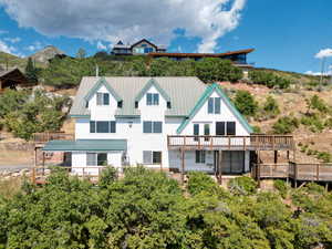 Back of house with a deck with mountain view and a standing seam roof