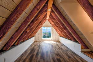 Bonus room featuring a wooden ceiling with exposed beams and dark wood-style floors