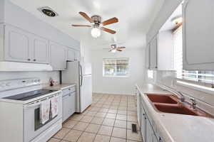 Kitchen featuring white appliances, light countertops, a ceiling fan, and light tile patterned flooring