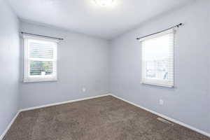 Spare room featuring dark carpet and healthy amount of natural light