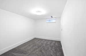 Unfurnished room with baseboards and dark carpet