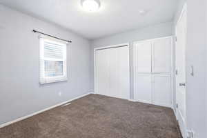 Unfurnished bedroom with dark colored carpet and a closet