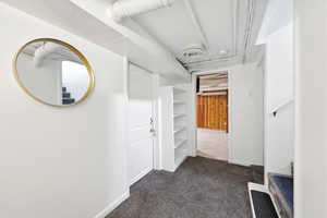 Hallway with dark carpet and baseboards