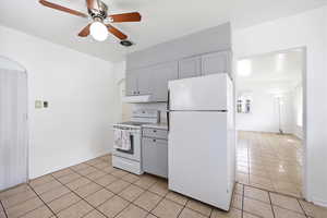 Kitchen with white appliances, ceiling fan, light countertops, light tile patterned flooring, and gray cabinetry