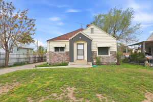 View of front facade featuring stone siding, a chimney, and a shingled roof