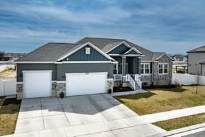 Craftsman house with stone siding, a garage, roof with shingles, and concrete driveway