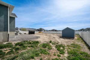 Fenced backyard featuring a residential view, a shed, and a mountain view