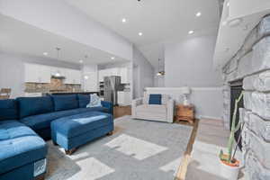 Living room featuring a fireplace, wood finished floors, recessed lighting, and lofted ceiling
