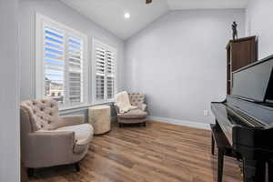 Sitting room with dark wood-style floors, lofted ceiling, custom shutters, and recessed lighting