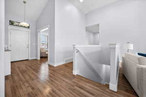 Open Foyer entrance featuring dark wood-style flooring and vaulted ceiling