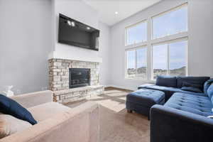 Living room featuring a stone fireplace, a cathedral ceiling, custom electric roller shades