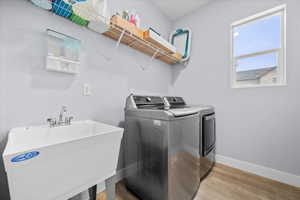 Laundry room featuring separate washer and dryer and light wood-style floors and sink