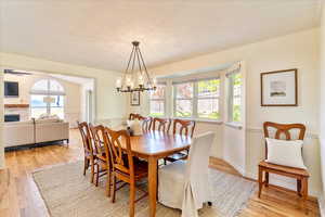 Dining space with light wood-style floors, hanging lights, a ceiling fan, ornamental molding, and a fireplace