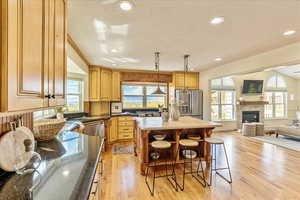 Kitchen with a center island, open floor plan, a breakfast bar, stainless steel appliances, and light wood-style flooring