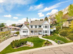 Traditional-style house with concrete driveway, a front lawn, covered porch, a mountain view, and a chimney