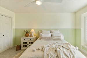 Bedroom with wainscoting, a textured ceiling, carpet flooring, a closet, and a ceiling fan