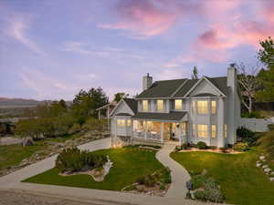 Traditional-style house with a porch, a yard, a chimney, and roof with shingles