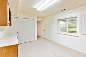 Unfurnished bedroom featuring a textured ceiling, a closet, and light carpet