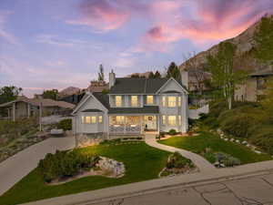 Traditional home featuring covered porch, a front yard, driveway, and a chimney