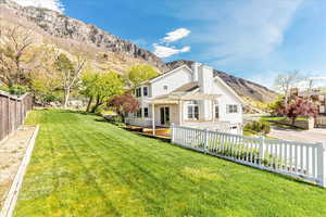 Rear view of house with a fenced backyard, a deck with mountain view, a chimney, and an attached garage