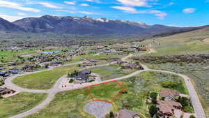 Aerial view of residential area with property boundaries highlighted and a mountainous background