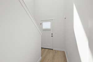 Doorway with baseboards and wood finished floors