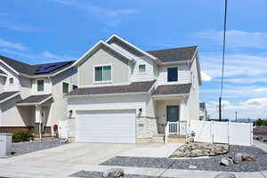 View of front of property with board and batten siding, a garage, concrete driveway, stone siding, and a gate