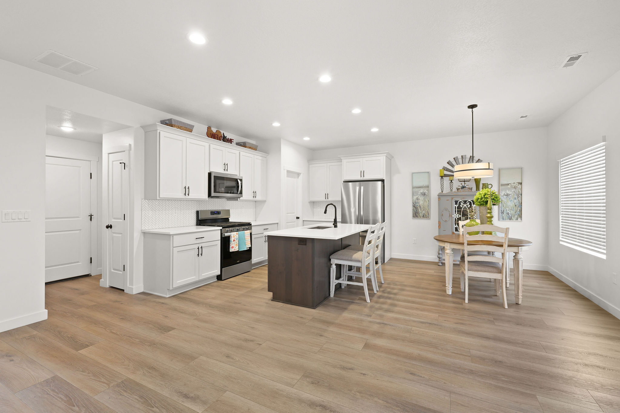 Kitchen with a kitchen breakfast bar, stainless steel appliances, an island with sink, dual tone cabinets, and hanging light fixtures