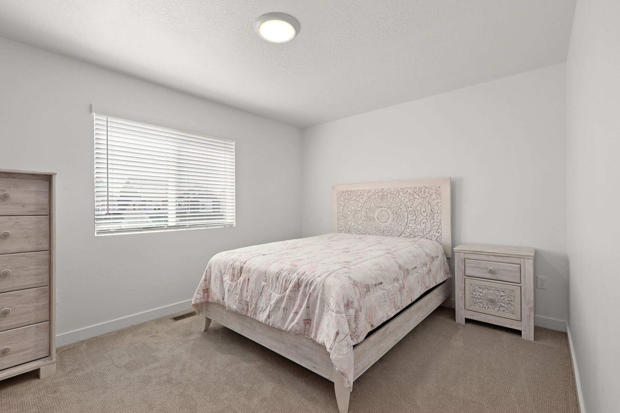 Bedroom with light colored carpet and a textured ceiling