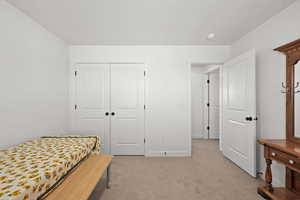 Bedroom with light colored carpet and a closet