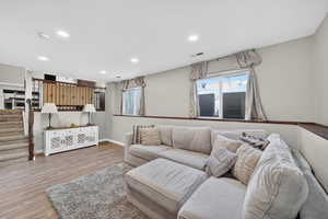 Living area with light wood-type flooring and recessed lighting