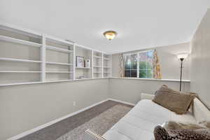 Unfurnished room featuring dark colored carpet and baseboards