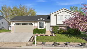 Tri-level home featuring brick siding, an attached garage, a shingled roof, and concrete driveway
