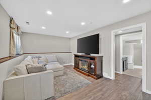 Living area featuring light wood-style floors, a glass covered fireplace, and recessed lighting