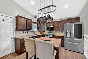 Kitchen with stainless steel appliances, light countertops, tasteful backsplash, dark wood finish cabinets, and light wood-style floors