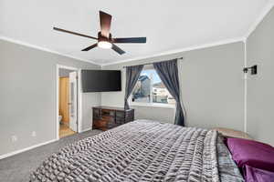 Bedroom with ornamental molding, light carpet, ceiling fan, and ensuite bathroom