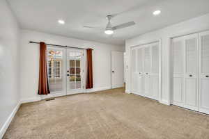 Unfurnished bedroom featuring french doors, two closets, light carpet, ceiling fan, and recessed lighting