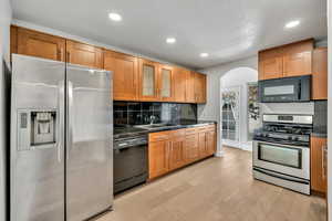 Kitchen featuring black appliances, dark countertops, light wood-style floors, recessed lighting, and wood finish cabinets
