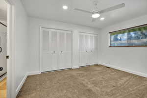 Unfurnished bedroom with multiple closets, ceiling fan, carpet flooring, and recessed lighting