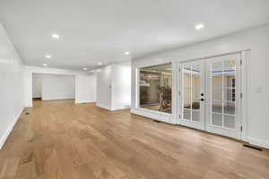Spare room with arched walkways, light wood finished floors, recessed lighting, and french doors