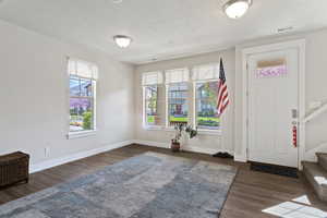 Foyer with dark wood-style floors and a textured ceiling