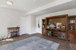 Living room featuring dark wood-style flooring and a brick fireplace