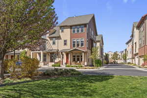 View of front of property with a front lawn, a residential view, stucco siding, and roof with shingles