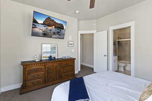 Bedroom featuring dark colored carpet, a ceiling fan, and connected bathroom