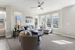 Living area with ceiling fan and baseboards