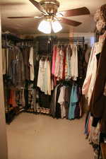 Walk in closet with light floors and ceiling fan
