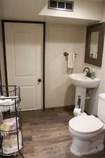 Half bathroom featuring wood finished floors and toilet